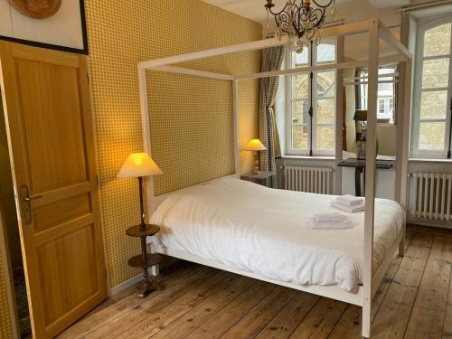 1 dormitorio con 1 cama blanca con dosel y 2 lámparas en Le Parvis, en Granville