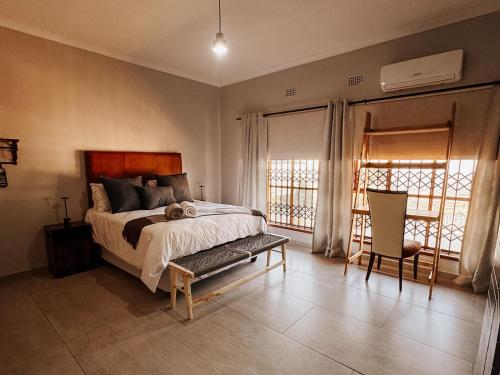 a bedroom with a bed and a chair and windows at Kudu Kopje Lodge in Kroondal