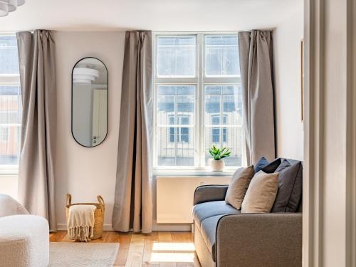 a living room with a couch and two windows at Sanders Regent Bright apartment in city center in Copenhagen