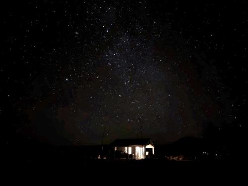 a starry sky with a small house at night at Kahurangi Cottage Twizel in Twizel
