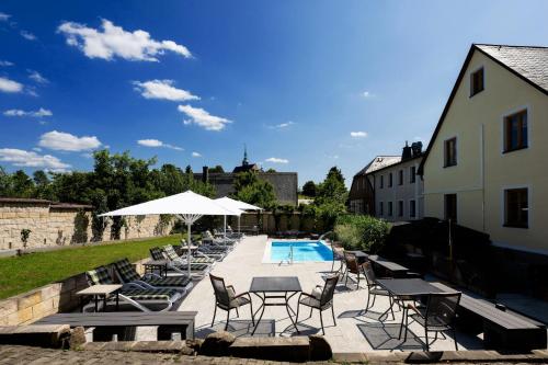 a group of chairs and tables next to a swimming pool at Landidyll Hinterhermsdorf by STEIGER Hotels in Hinterhermsdorf