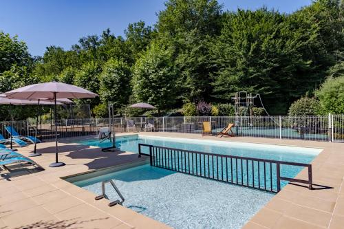 - une piscine avec un parasol, des chaises et un parasol dans l'établissement Maison Rose, à Castelnaud-la-Chapelle
