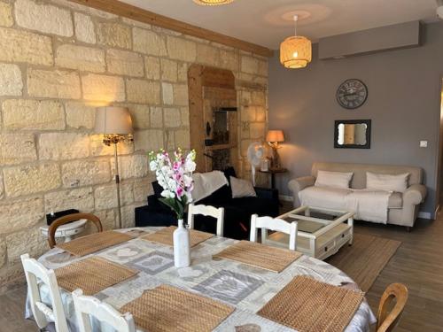 a living room with a table and a stone wall at Bel appartement en pierre de 100 m2 avec cour. in Margaux