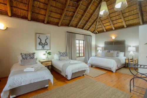a bedroom with two beds and a wooden ceiling at Stay at Royal in Marloth Park