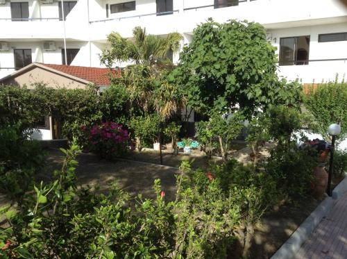 a garden in front of a building with trees and bushes at Vasilina in Faliraki