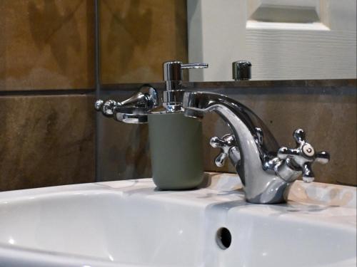 a bathroom sink with a faucet and a cup on it at Waterwoods Equestrian Venue and Cottages in Nottingham Road