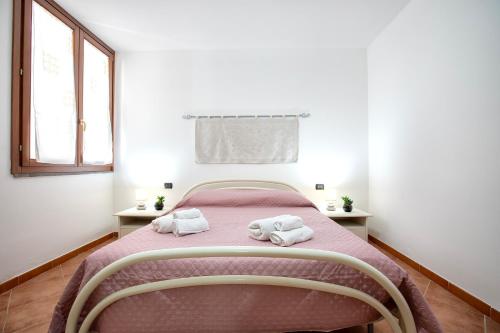 Un dormitorio con una cama rosa con toallas. en Villa Marina, en Alghero