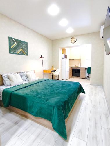 a bedroom with a green bed and a kitchen at Радужная студия Вокзал Харьков-Пассажирский in Kharkiv