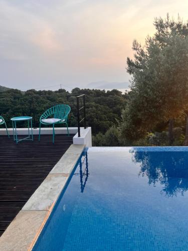 a swimming pool with two chairs sitting next to it at Allure Luxury Villas 2, Skiathos in Skiathos Town