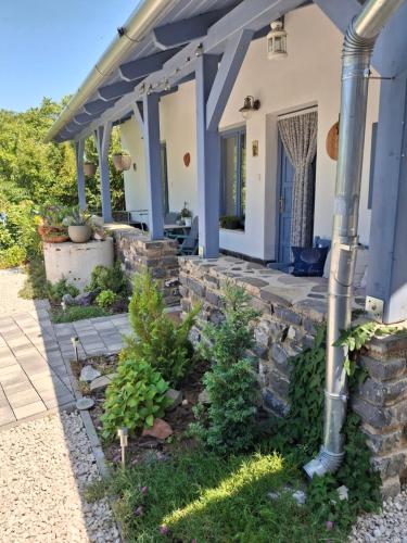 a front porch of a house with a stone wall at Kékbazalt Vendégház in Badacsonytomaj