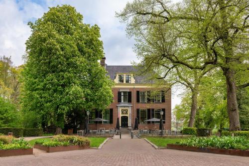 a large brick house with trees in front of it at Stayokay Hostel Utrecht - Bunnik in Bunnik