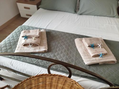 a bed with two towels and a basket on it at Nima in Porto Santo Stefano