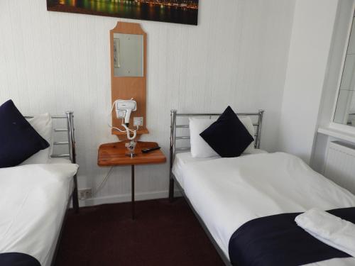 a room with two beds and a phone on a table at All Seasons Gatwick Guest House & Parking in Horley