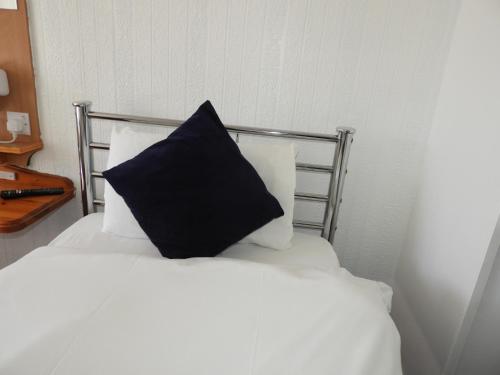 a black pillow sitting on top of a white bed at All Seasons Gatwick Guest House & Parking in Horley