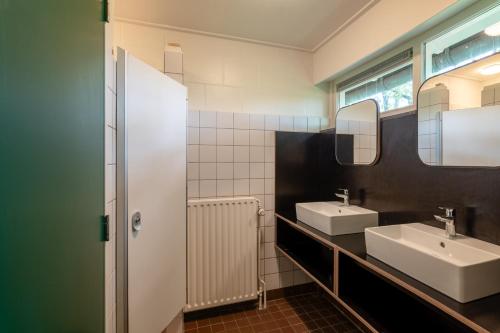 a bathroom with two sinks and a mirror at Stayokay Hostel Utrecht - Bunnik in Bunnik