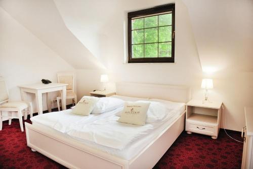 a bedroom with a white bed with two tables and a window at Malutkie Resort in Radomsko