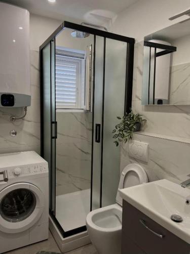 a bathroom with a shower and a washing machine at Moretino Supetar in Supetar