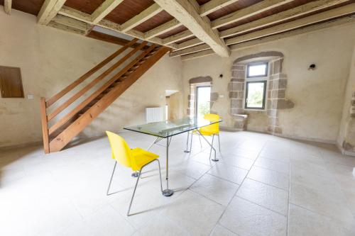 une salle à manger avec une table en verre et des chaises jaunes dans l'établissement Château de Chausserais, à Chiché