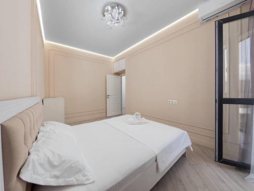 a white bedroom with a bed and a window at Terracotta Elite Apartments in Almaty