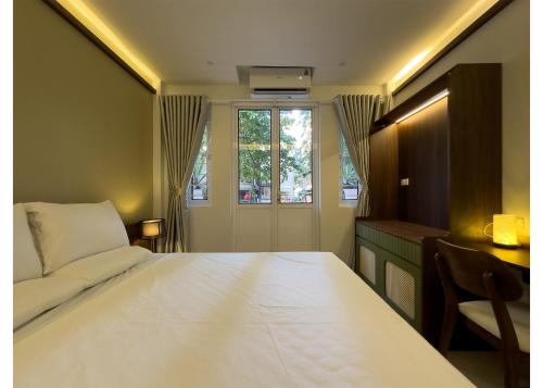 a bedroom with a bed and a couch and a window at Bamboura Home in Hanoi
