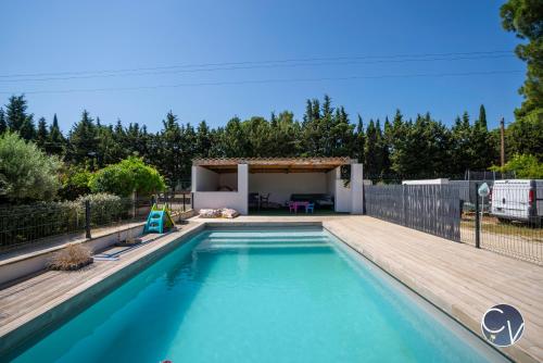 - une piscine dans un jardin avec une terrasse en bois dans l'établissement Appartement avec Piscine proche Avignon et Uzes, à LʼArdoise