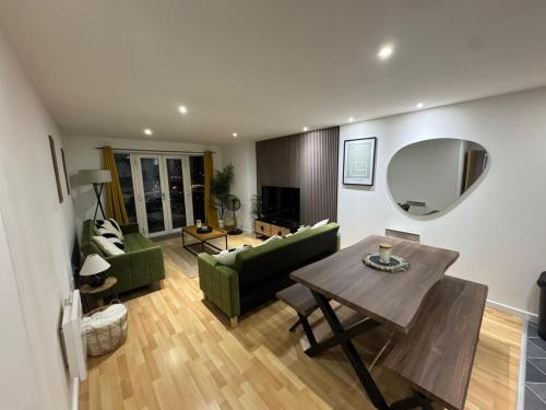 Modern 2BR Apartment City Centre Free Secure Parking Stunning Views في برمنغهام: غرفة معيشة مع أريكة خضراء وطاولة
