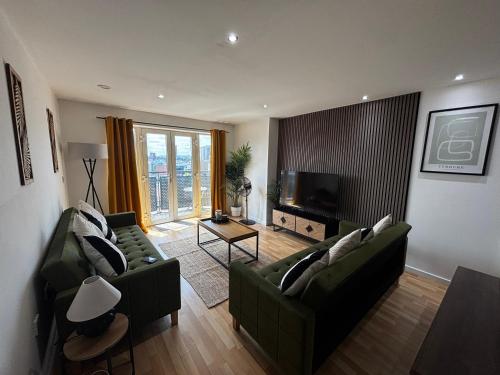 a living room with two green couches and a television at Modern 2BR Apartment City Centre Free Secure Parking Stunning Views in Birmingham