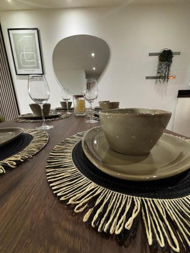 einen Tisch mit einer Schüssel und Weingläsern darauf in der Unterkunft Elegant TWO Bedroom Apartment Amazing Views Birmingham City Centre FREE Underground Parking in Birmingham