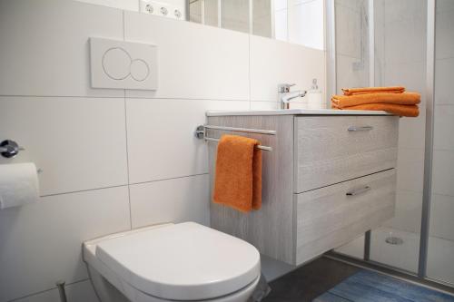 La salle de bains est pourvue de toilettes et d'un lavabo avec des serviettes orange. dans l'établissement Ferienwohnung Morgensonne, à Wolfach