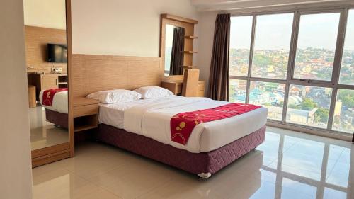 a hotel room with a bed and a large window at RedLiving Star Apartemen Semarang - UMAKU Lantai 16 in Jomblang