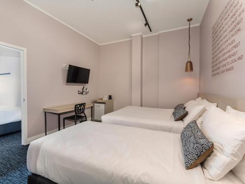 ein Hotelzimmer mit zwei Betten und einem Schreibtisch in der Unterkunft Nightcap at Belgian Beer Cafe in Perth