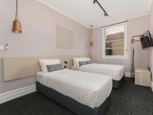 two beds in a room with white walls and a window at Nightcap at Belgian Beer Cafe in Perth