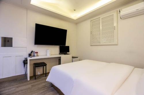 a white bedroom with a bed and a television at Anyang Sky Castle in Anyang
