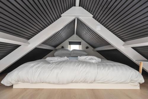 ein Schlafzimmer mit einem großen weißen Bett im Dachgeschoss in der Unterkunft Flamingo Beach Apartments in Zandvoort