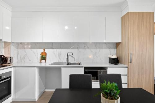 a kitchen with white cabinets and a black table at Coastal Comfort in Rockingham 2BR Apartment with Parking & Balcony in Rockingham