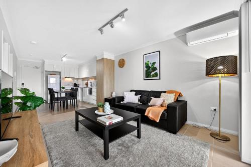 a living room with a black couch and a table at Coastal Comfort in Rockingham 2BR Apartment with Parking & Balcony in Rockingham