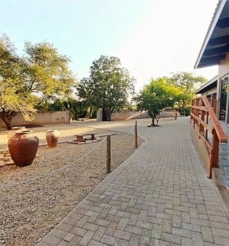 a brick sidewalk next to a building with a bench at Ukulala Inn in Malelane