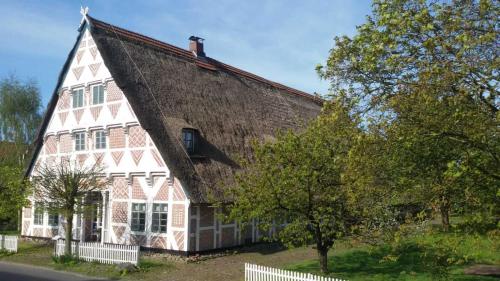 a large red and white building with a tree at Denkmalgeschütztes Ferienidyll unter Reet in Guderhandviertel