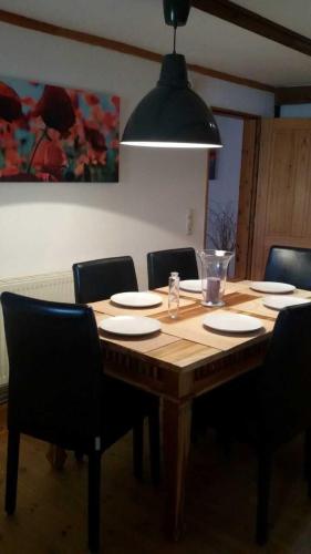 a dining room table with chairs and aendant light at Denkmalgeschütztes Ferienidyll unter Reet in Guderhandviertel