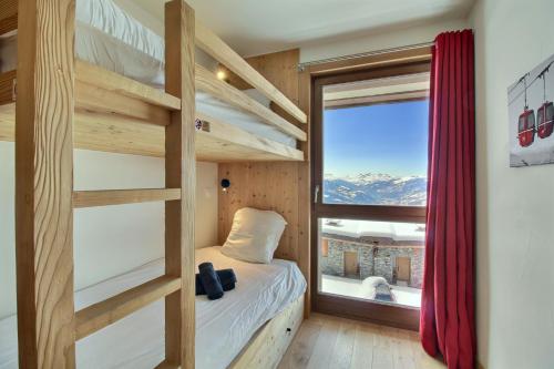 a small bedroom with bunk beds and a window at ARC 1600, LE RIDGE, Appartement 10 personnes Duplex Vue Montagne - ski aux pieds - Sauna, Hammam, Piscine, Salle de salle de sport-fitness in Arc 1600