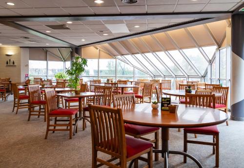 un restaurant avec des tables et des chaises en bois et des fenêtres dans l'établissement B&B HOTEL Grenoble Université 2, à Gières