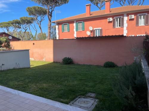 an orange house with a yard with a fence at Casa Junea in Maccarese