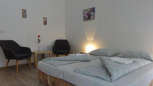 a bedroom with a bed with two chairs and a table at Penzion U Hradeb in Znojmo