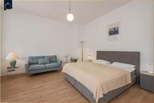 ein Schlafzimmer mit einem Bett und einer blauen Couch in der Unterkunft Villa Martha Apartment 3 in Heringsdorf