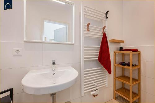 ein weißes Badezimmer mit Waschbecken und Spiegel in der Unterkunft Villa Martha Apartment 3 in Heringsdorf