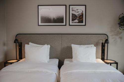 two beds with white sheets and two pictures on the wall at Home Hotel Etage in Västerås