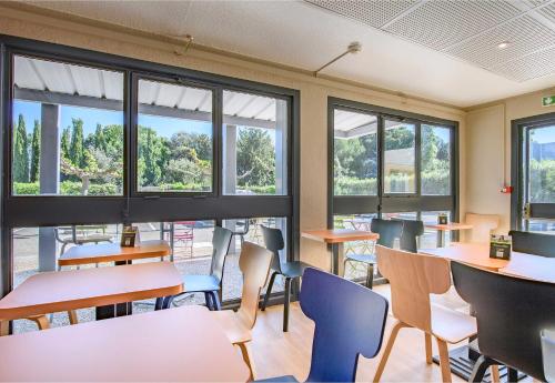a classroom with tables and chairs and windows at B&B HOTEL Nîmes Caissargues in Caissargues