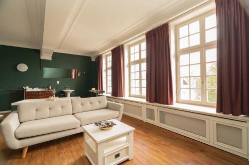 a living room with a couch and some windows at Hotel Restaurant Steenhuyse in Oudenaarde