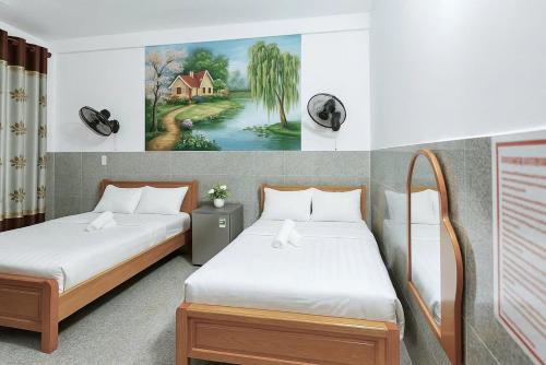 two beds in a room with a painting on the wall at Ngọc Hoa - Nam Hội An Hotel in Thăng Bình