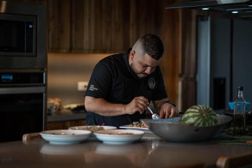 a man standing in a kitchen preparing food in a bowl at Villa Kañik - Luxury Retreat with Concierge Services in Dominical